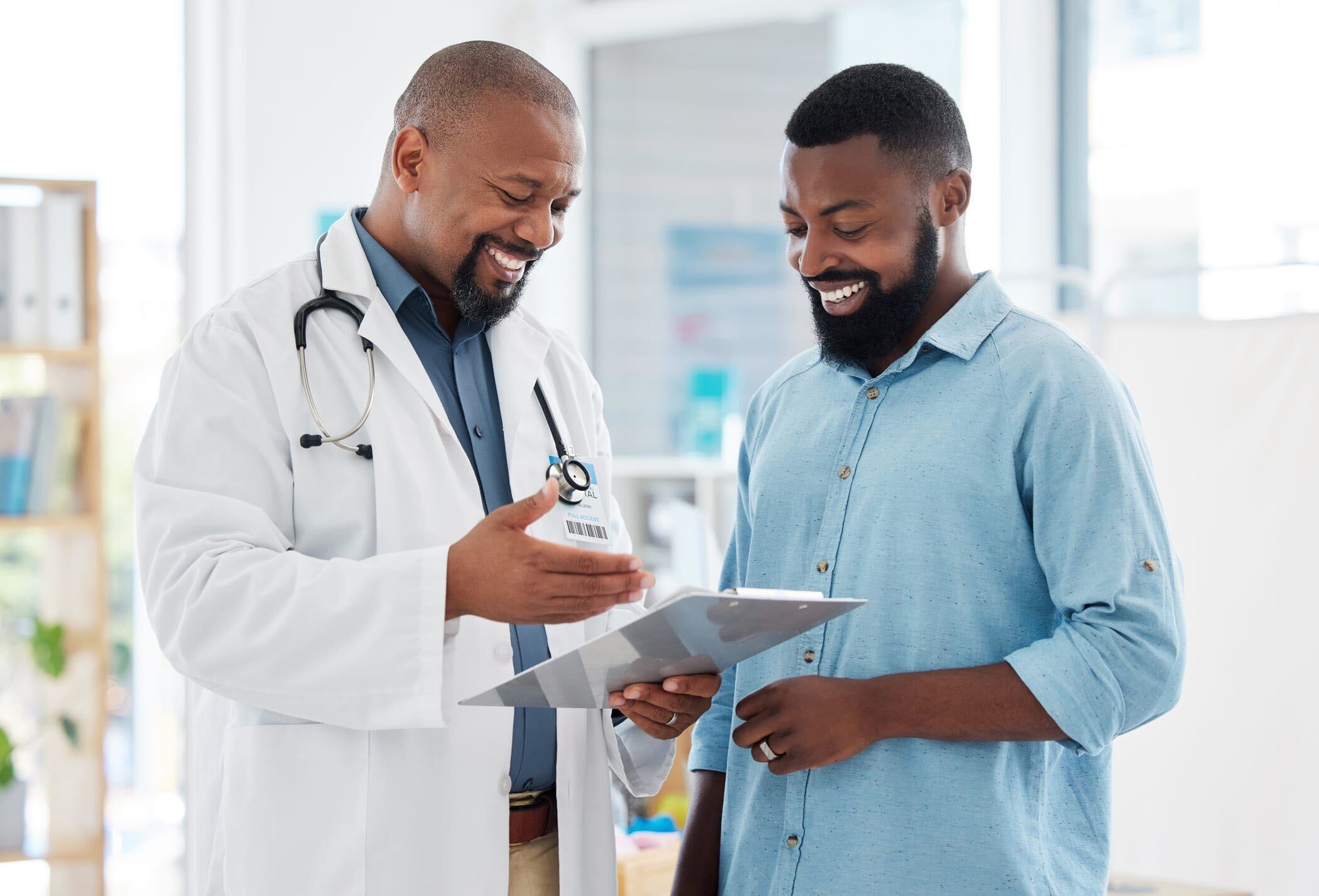 A black male doctor smiling with his black male patient