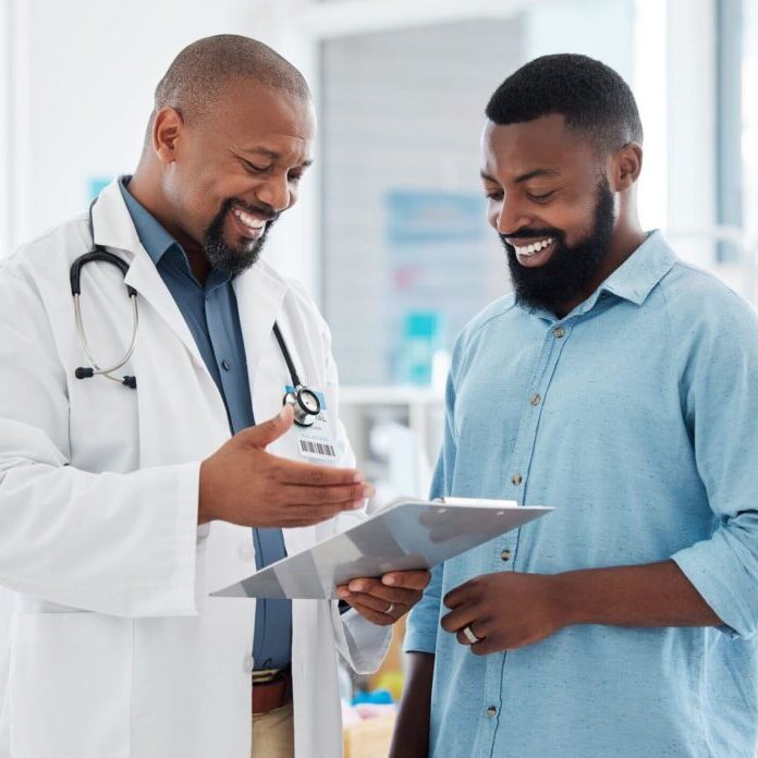 A black male doctor smiling with his black male patient